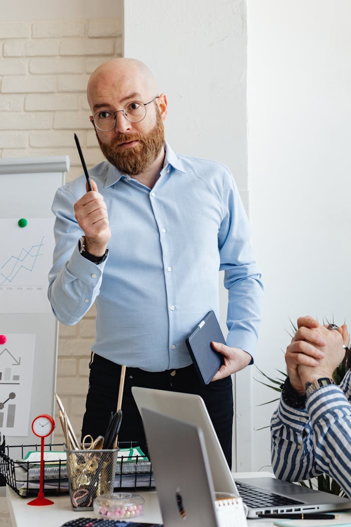 Bald businessman with beard giving a presentation in a modern office setting.